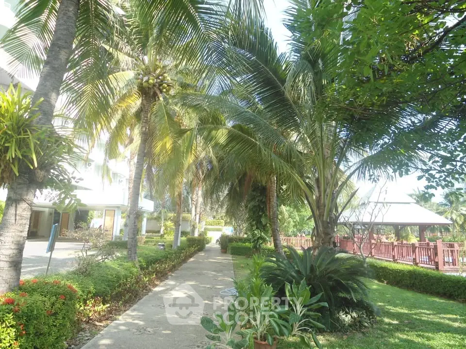 Lush garden pathway with tropical palm trees and vibrant greenery in a serene residential setting.
