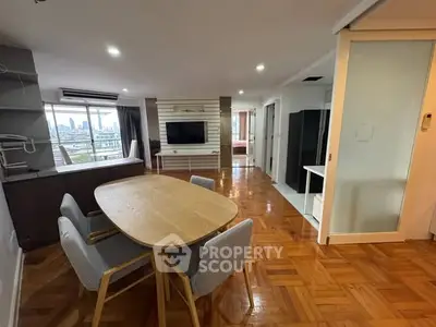 Spacious open-plan living and dining area with city view, featuring modern furniture and wooden flooring.