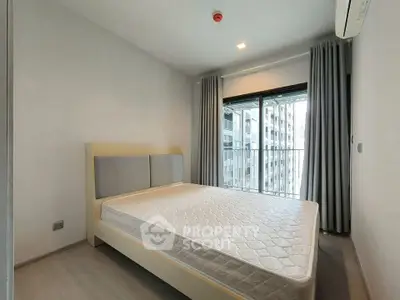 Modern bedroom with large window and city view, featuring a comfortable bed and stylish curtains.