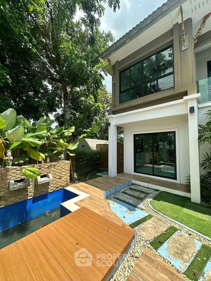 Stunning modern home exterior with lush garden and water feature, perfect for serene living.