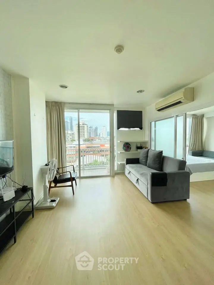 Spacious modern living room with city view, featuring sleek furniture and large windows.