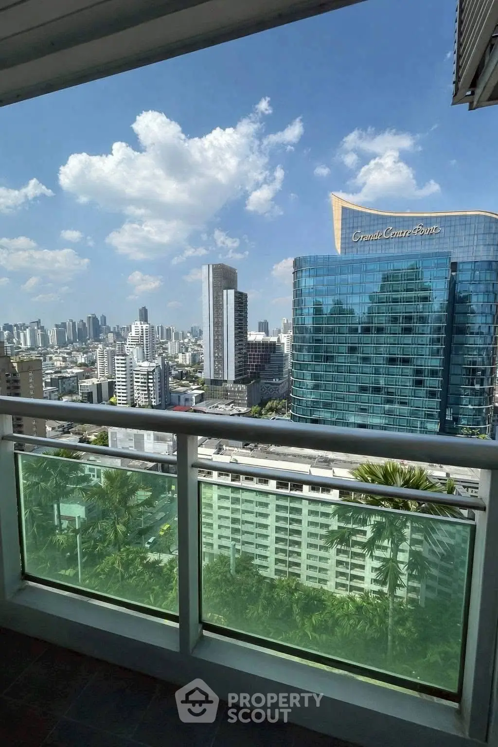 Stunning cityscape view from a high-rise balcony with modern architecture and clear blue skies.