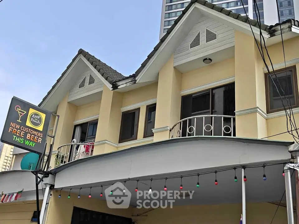 Charming yellow building with unique architectural design and inviting balcony, perfect for new customers.