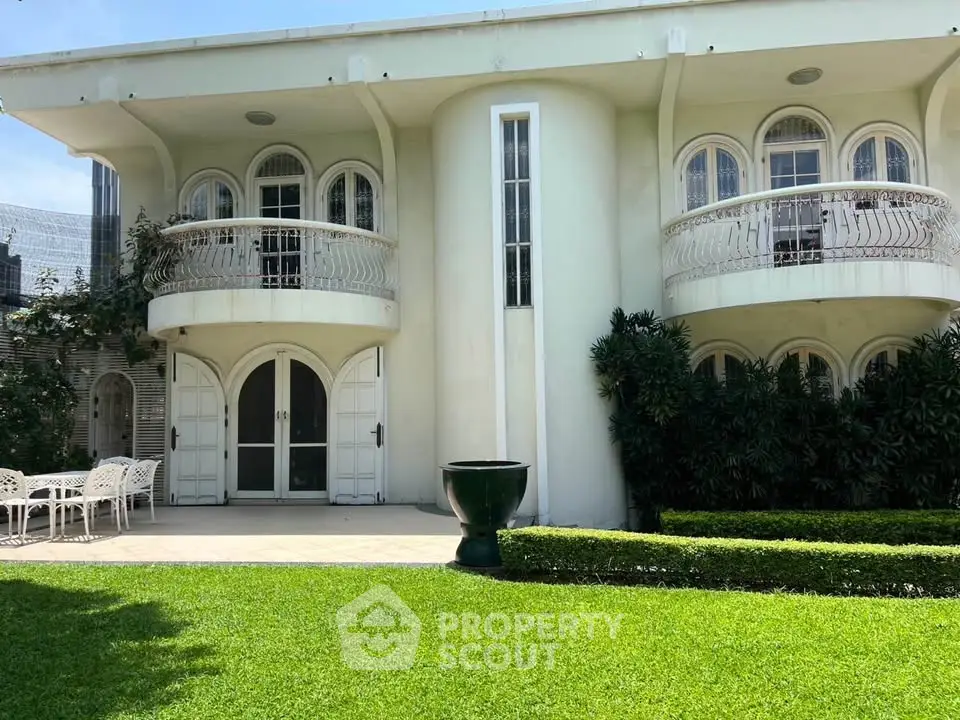 Elegant two-story building with arched windows and lush green lawn