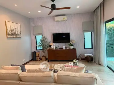 Stylish living room with modern decor, ceiling fan, and natural light from large windows.