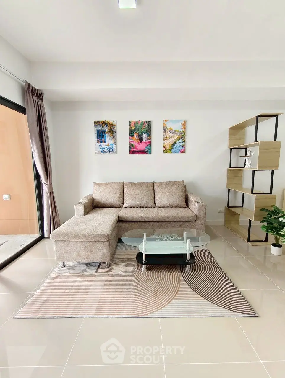 Modern living room with stylish sofa, glass coffee table, and decorative shelving unit.