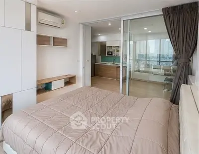 Modern bedroom with sliding glass doors leading to a stylish kitchen, featuring contemporary design and ample natural light.
