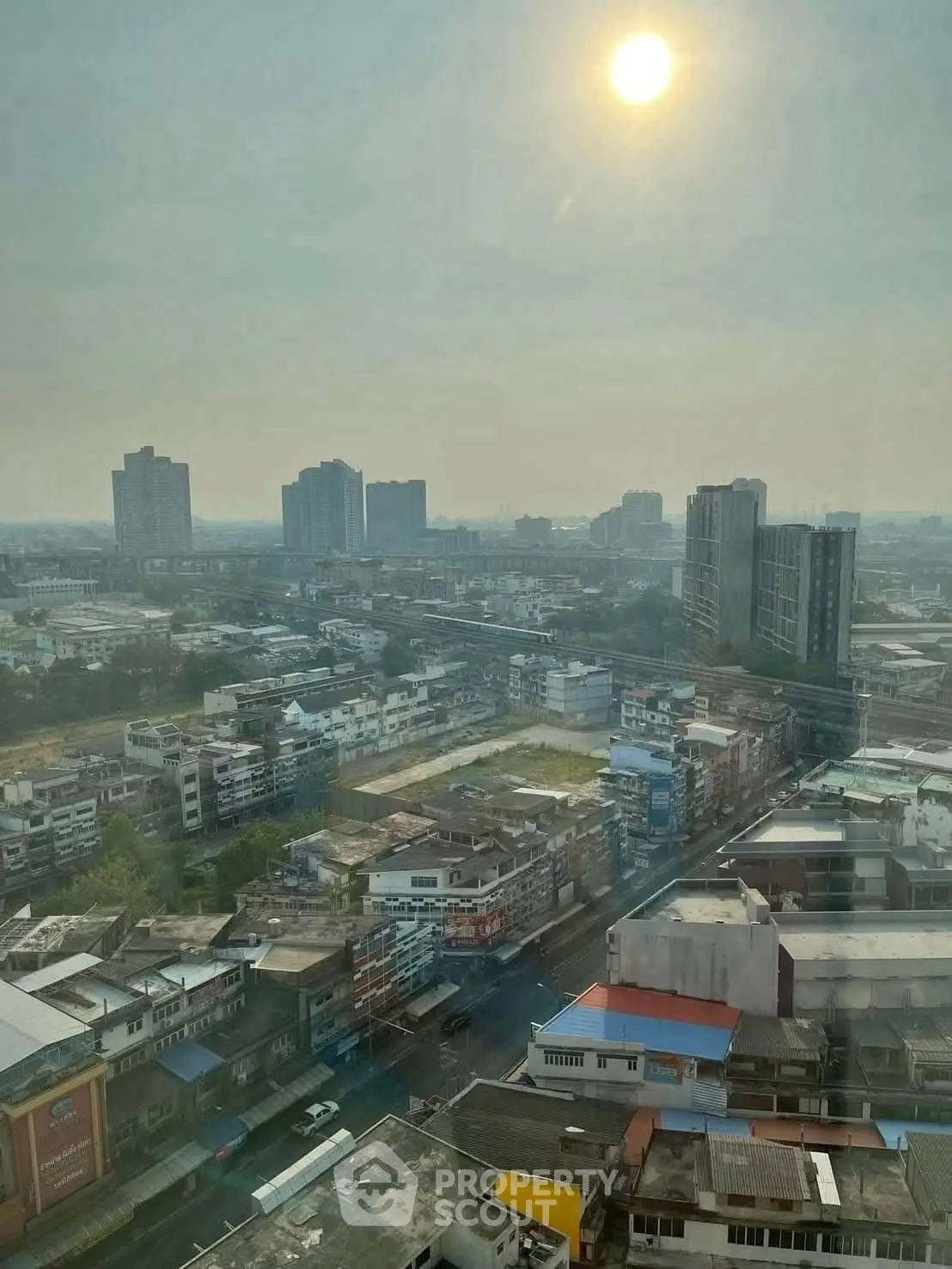 Stunning cityscape view from high-rise building showcasing urban skyline under a hazy sun.