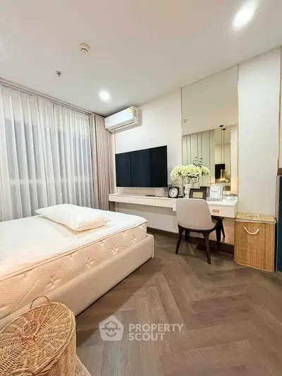 Modern bedroom with elegant decor, featuring a large TV, stylish furniture, and soft lighting for a cozy ambiance.