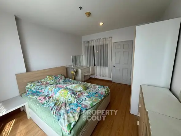 Spacious bedroom with wooden flooring and modern furniture