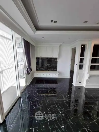 Luxurious living room with elegant black marble flooring and built-in cabinetry, featuring large windows for natural light.