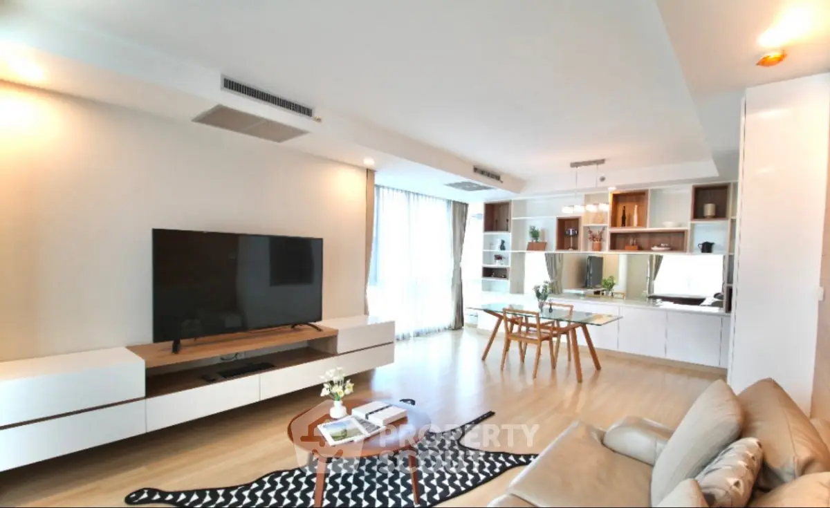 Spacious modern living room with large TV, stylish furniture, and ample natural light.