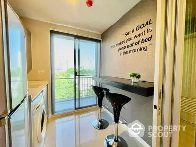 Modern kitchen with breakfast bar and city view, featuring sleek appliances and motivational wall quote.