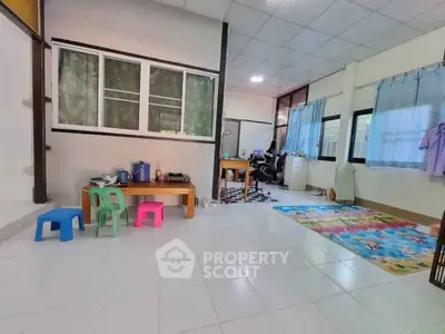 Spacious living area with tiled floor and large windows, ideal for family gatherings.