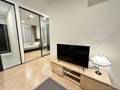 Modern living room with TV and view into bedroom, featuring sleek wooden flooring and stylish decor.