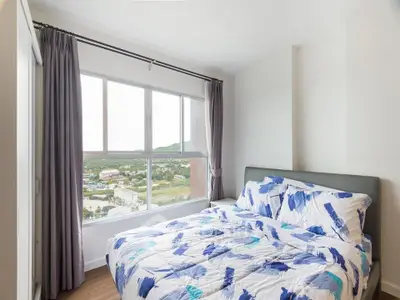Bright bedroom with large window offering scenic views, modern decor, and cozy bedding.
