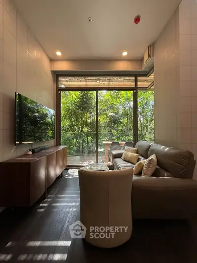 Modern living room with large windows and lush garden view, featuring cozy seating and sleek decor.