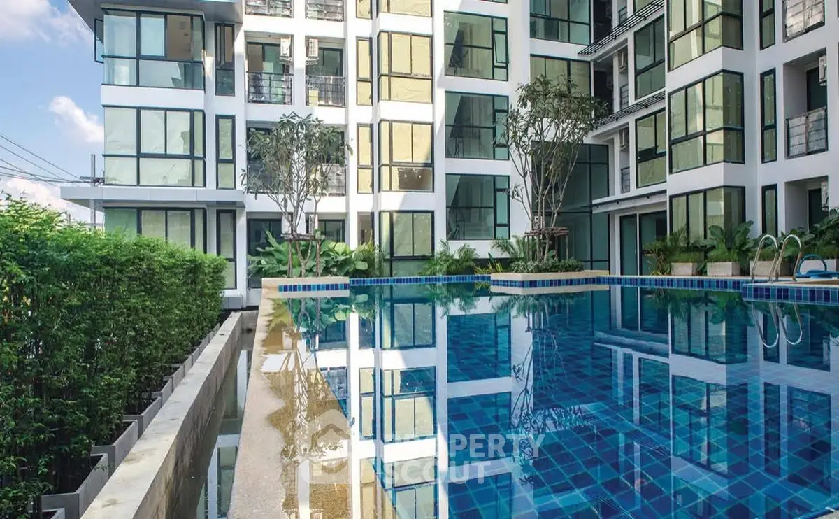 Modern apartment building with a luxurious outdoor pool and lush greenery.