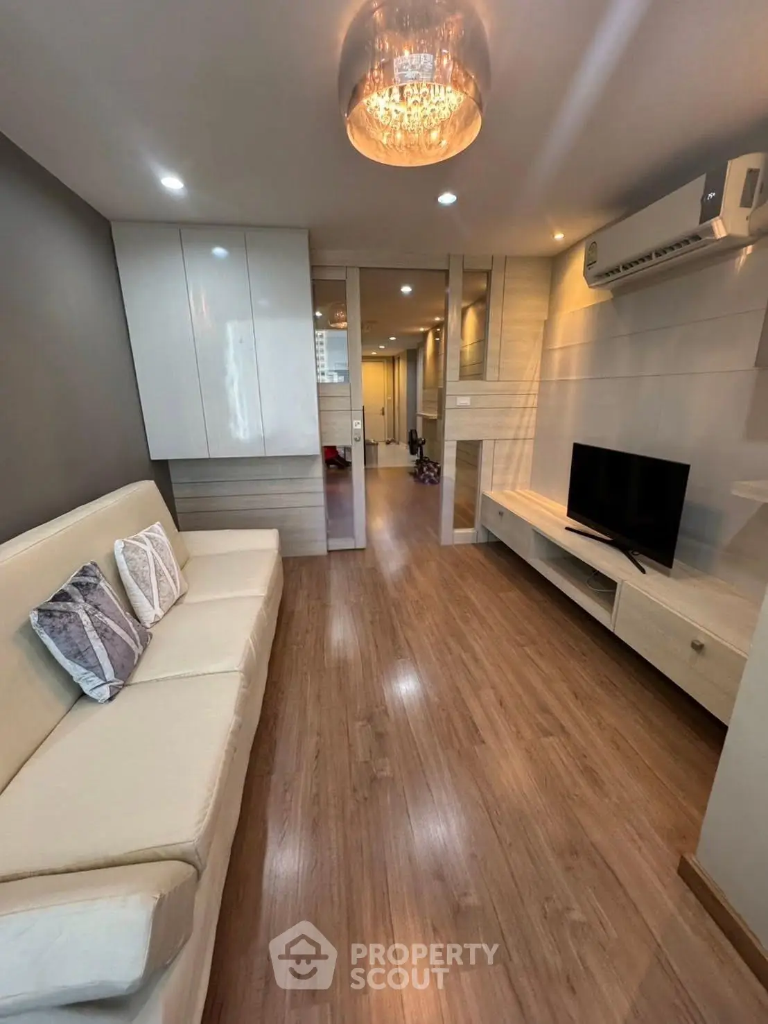 Modern living room with sleek design, featuring a cozy sofa, flat-screen TV, and elegant lighting.