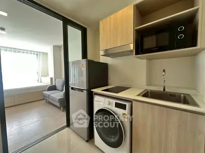 Modern compact kitchen with washing machine and microwave in a cozy apartment