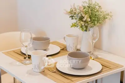 Elegant dining setup with modern tableware and floral centerpiece in cozy apartment.
