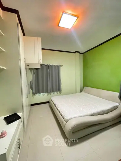 Cozy bedroom with modern design and stylish green accent wall.