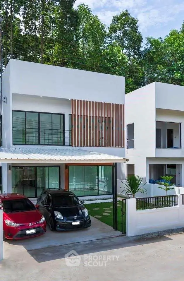 Modern two-story house with carport and sleek design in a lush green setting.