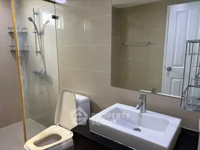 Modern bathroom with sleek fixtures and glass shower enclosure in a contemporary home.