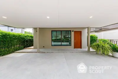 Modern house entrance with spacious driveway and lush greenery