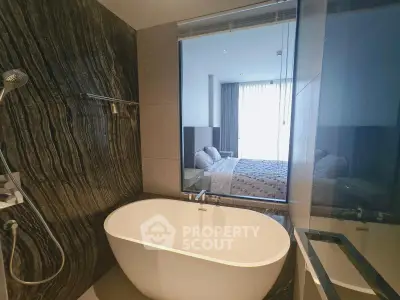 Luxurious bathroom with modern bathtub and view into elegant bedroom