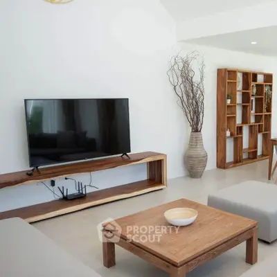Modern living room with sleek wooden furniture and large flat-screen TV.