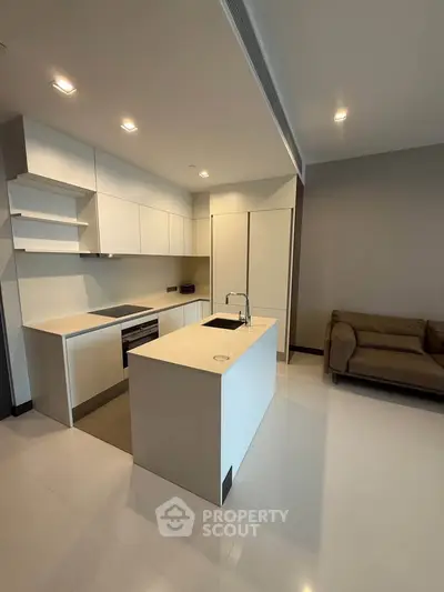 Modern kitchen with sleek white cabinetry and island in open layout apartment.