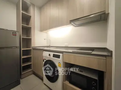 Modern kitchen with washing machine, microwave, and sleek cabinetry