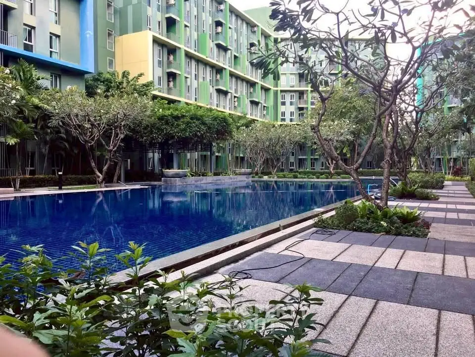 Modern apartment complex with lush garden and inviting pool area.