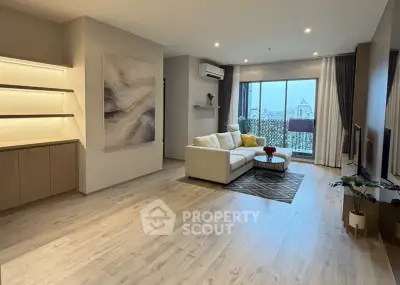 Spacious modern living room with large windows and city view, featuring elegant decor and cozy seating area.