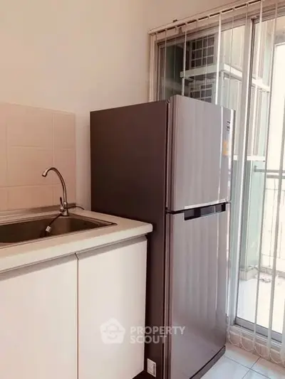 Modern kitchen with sleek fridge and sink near balcony, perfect for urban living.