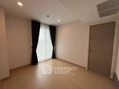 Spacious empty room with wooden flooring and large window in modern apartment