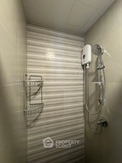 Modern bathroom shower area with sleek tile design and water heater.