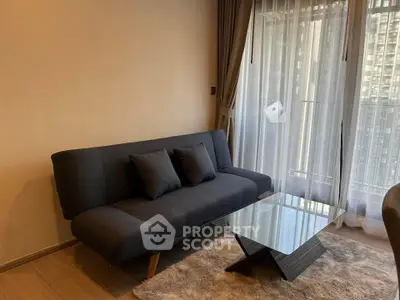 Modern living room with stylish sofa and glass coffee table, featuring floor-to-ceiling windows with city view.