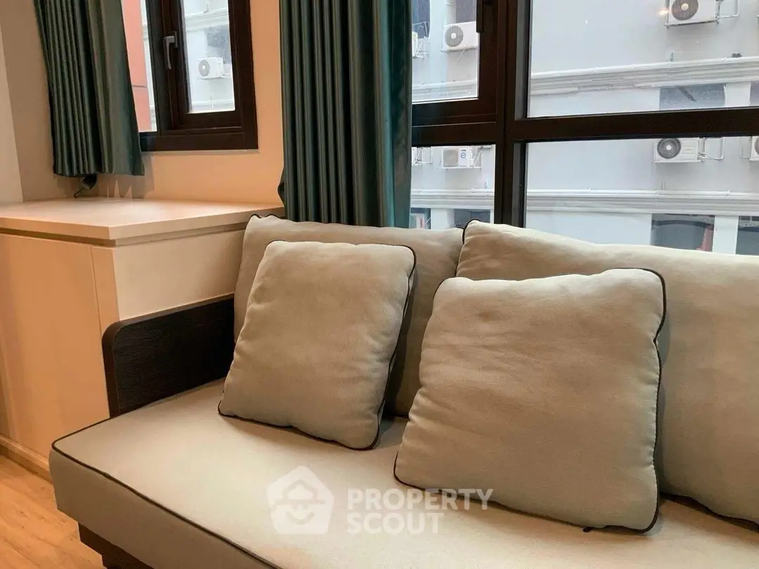 Cozy living room with modern sofa and large windows offering city views.