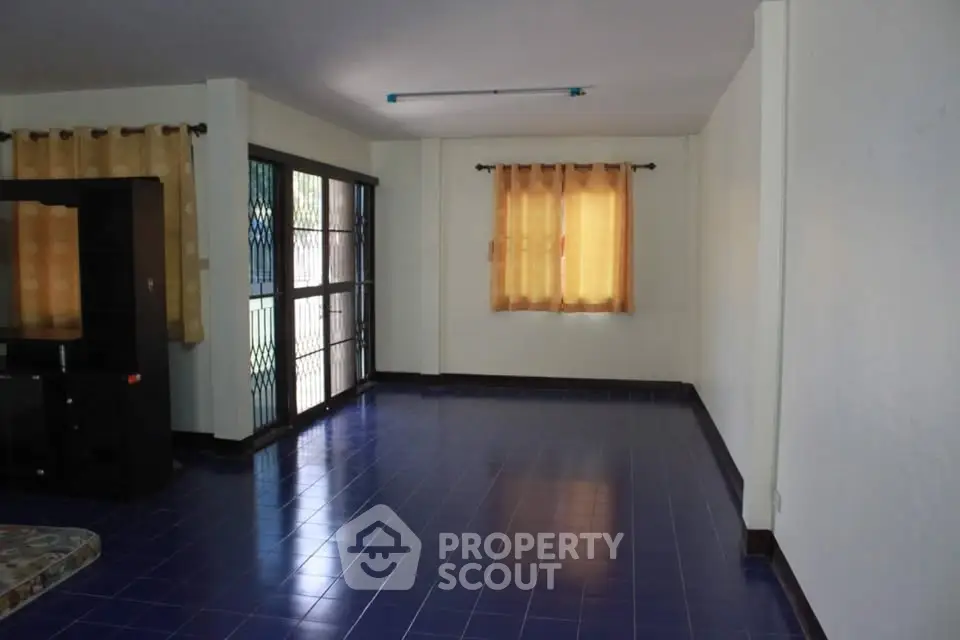 Spacious living room with blue tiled floor and large windows for natural light.