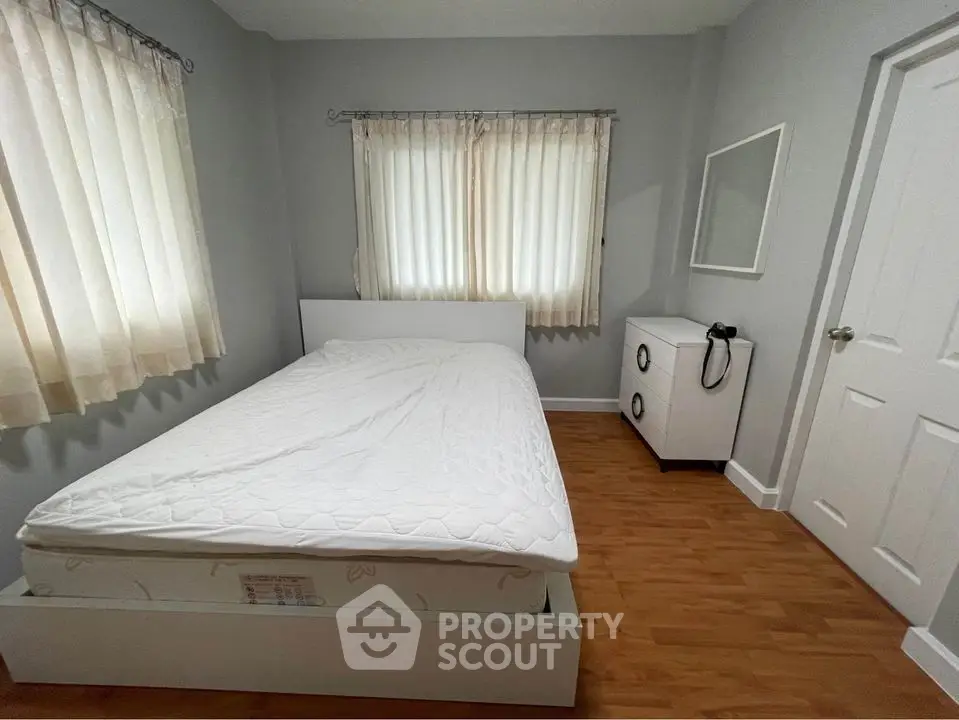 Cozy bedroom with natural light, featuring a comfortable bed and minimalist decor.