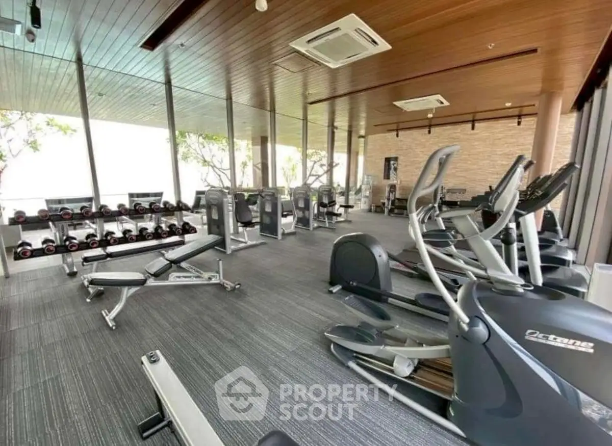 Modern gym with state-of-the-art equipment and floor-to-ceiling windows offering a bright workout space.