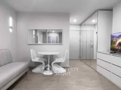 Modern minimalist living room with sleek white furniture and mirrored closet doors.