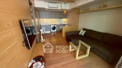 Modern open-plan living room with kitchen and washing machine, featuring wooden flooring and stylish decor.