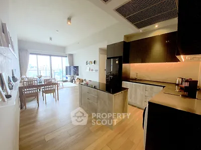 Spacious modern living room with open kitchen and large windows offering city views.