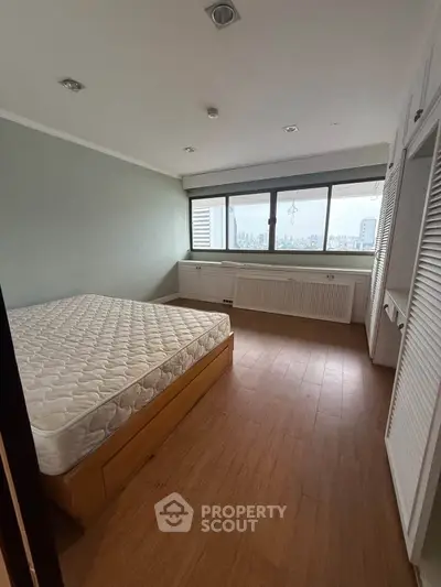 Spacious bedroom with large window offering city views and ample natural light.