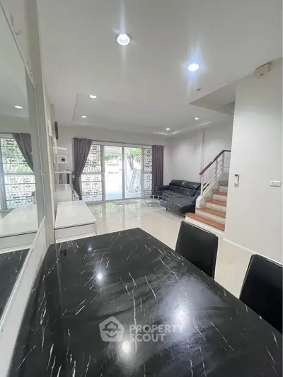 Spacious modern living room with sleek black marble dining table and elegant staircase