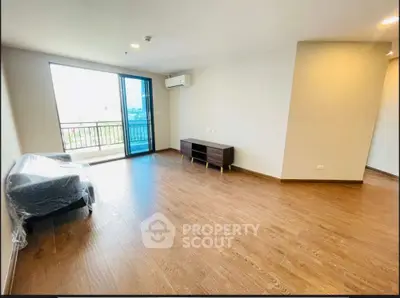 Spacious living room with wooden flooring and balcony access in modern apartment.
