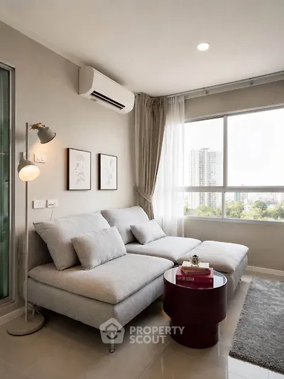 Modern living room with large window and city view, featuring stylish furniture and elegant decor.